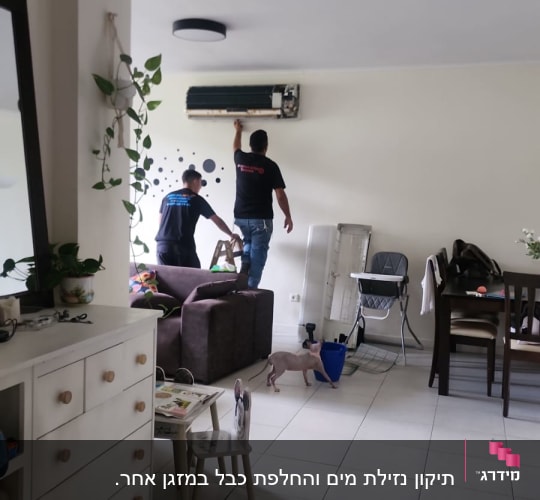 שני אנשים מתקנים מזגן על קיר בסלון